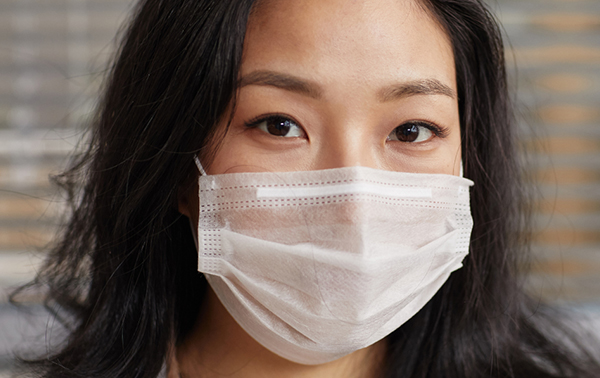 A young asian woman wearing a surgical mask.