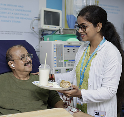 A woman in a hospital bed receiving a plate from a doctor.